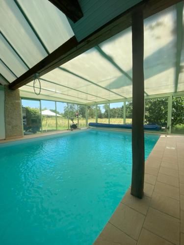 une grande piscine avec un toit clair dans l'établissement La Parenthèse - Studio atypique - Piscine - Proche Le Mans, à Amné-en-Champagne