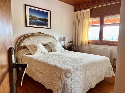 una camera da letto con un letto con lenzuola bianche e una finestra di Piso Puigcerda vistas y piscina a Puigcerdà