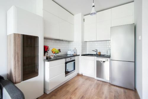 cocina blanca con electrodomésticos blancos y suelo de madera en Apartament Lema en Gdansk