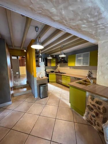 une grande cuisine avec des placards jaunes et verts et un comptoir dans l'établissement Maison de campagne style mas, à Camélas