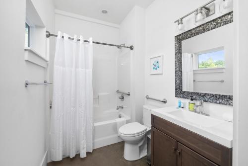 a bathroom with a toilet and a sink and a mirror at The Polygon Park Circle Mins to Dwtn and Beach in Charleston