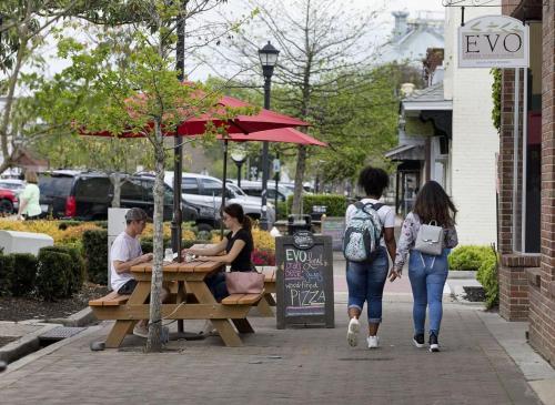 a group of people sitting at a picnic table on a sidewalk at The Polygon Park Circle Mins to Dwtn and Beach in Charleston