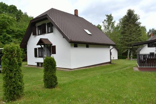 a white house with a black roof at Vadása Nyaraló in Hegyhátszentjakab