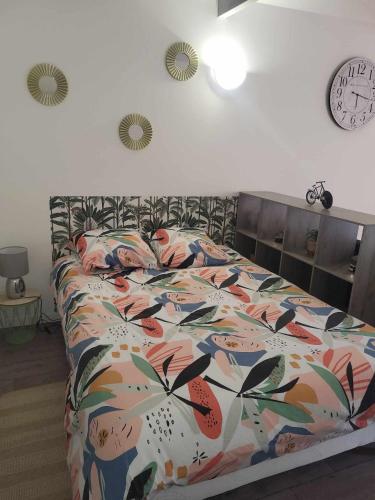 - un lit avec une couette colorée et une horloge murale dans l'établissement Petite maison Juvisy, Orly 7 min, Paris 15min, à Juvisy-sur-Orge