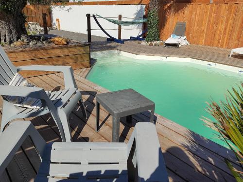 - une piscine avec une chaise, une table et un banc dans l'établissement cottage la dune les cigales du bassin à Gujan-Mestras, à Gujan-Mestras