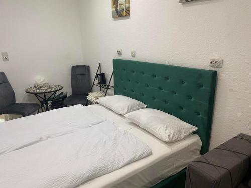 a bedroom with a large bed with a green headboard at Mrkonjić Grad Apartmani in Mrkonjić Grad
