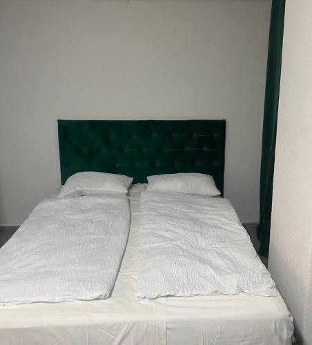 a bed with two white sheets and a green headboard at Mrkonjić Grad Apartmani in Mrkonjić Grad