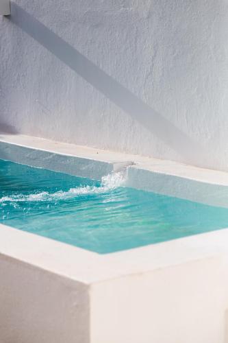 a swimming pool with blue water in a building at Calma Boutique House in Vila Nova De Cacela