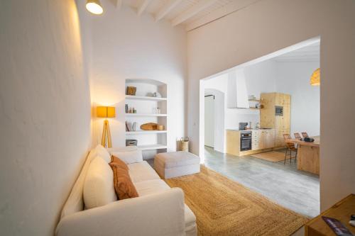 a living room with a white couch and a kitchen at Calma Boutique House in Vila Nova De Cacela