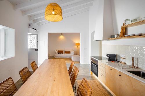 a kitchen and dining room with a wooden table and chairs at Calma Boutique House in Vila Nova De Cacela