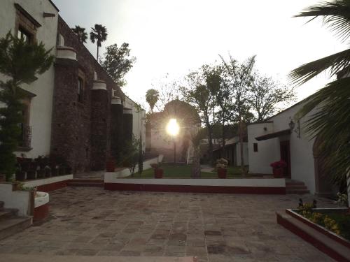 a courtyard of a building with a sunset in the background at Hotel Spa Hacienda Real la Nogalera in Tequisquiapan