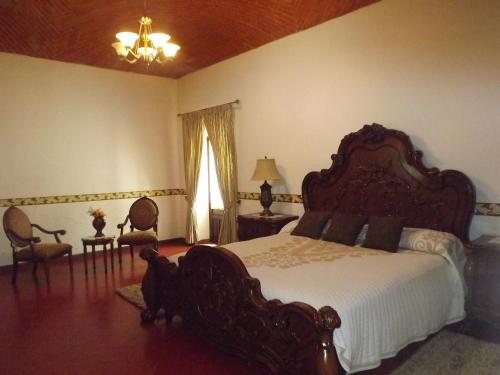 a bedroom with a large bed and two chairs at Hotel Spa Hacienda Real la Nogalera in Tequisquiapan