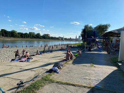 a group of people sitting on the beach near the water at Wellness Apartment Kalypso in Osijek