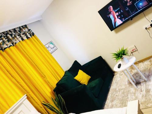 a living room with a green couch and a yellow curtain at Indesign Makumbi park studio Apartment D4-5,Syokimau in Syokimau