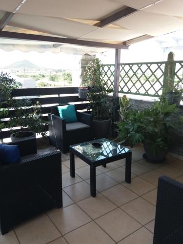 a patio with a table and chairs and potted plants at Green House in Néa Péramos