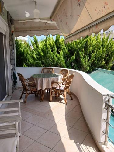 a patio with a table and chairs and a swimming pool at Green House in Néa Péramos