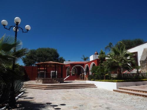 a red building with a gazebo and palm trees at Hotel Spa Hacienda Real la Nogalera in Tequisquiapan
