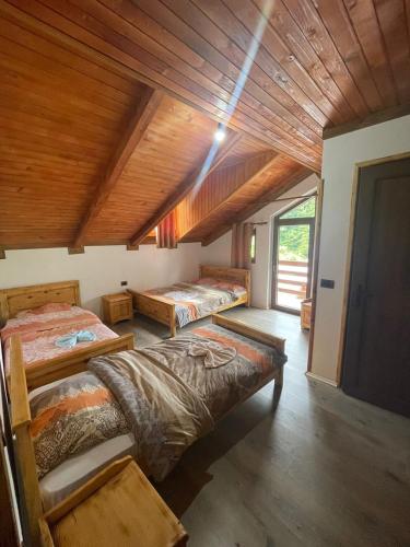 Habitación con 3 camas y techo de madera. en natyra balcony, en Valbonë
