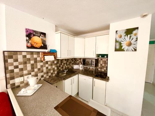 uma pequena cozinha com armários brancos e uma bancada em Borinquen Sky Apartments em Playa de las Americas