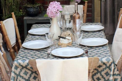 a table with plates and glasses and a vase with flowers at Sea Proche in Sandown