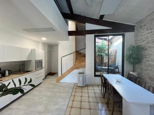 une cuisine avec des armoires blanches et une table avec des chaises dans l'établissement LOFT-HOLIDAY 3 Appartement spacieux à proximité de la plage, à Pinet