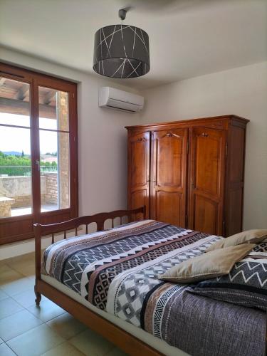 1 dormitorio con 1 cama con armario de madera y ventana en Maison Provençale Spa Sauna Piscine en Mollégès
