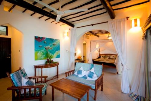 a living room with a bed and a table and chairs at Turtle Bay Beach Club in Watamu