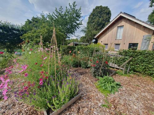 a garden with flowers in front of a house at Recreatiewoning De NieuwenHof in Melderslo