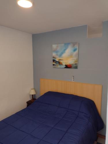 Un dormitorio con una cama azul y una pintura en la pared en Centrico Pichincha cercano al rio en Rosario