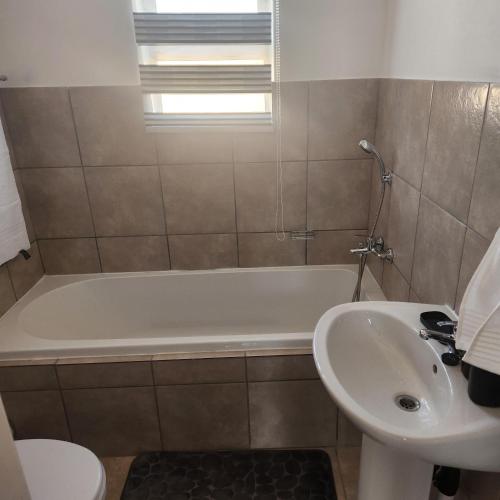 uma casa de banho com uma banheira branca e um lavatório. em Two Bedroom townhouse THE PINES ALBERTSDAL em Alberton