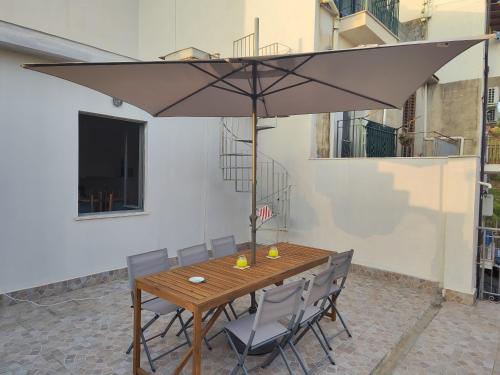 a wooden table with chairs and an umbrella at Borgo Di Taormina Apartments in Gaggi