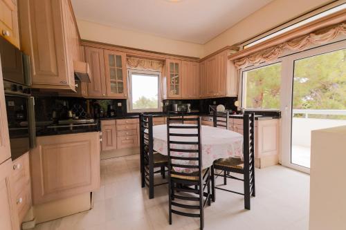 a kitchen with wooden cabinets and a table and chairs at Zeusplace PoolVilla Natura Paralia Katerini in Katerini