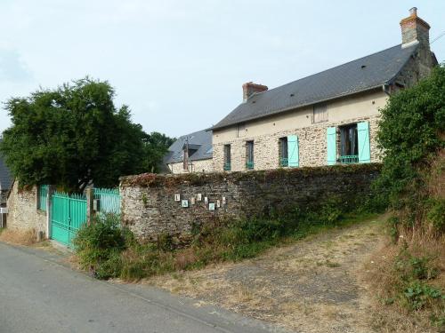 uma antiga casa de tijolos com portas verdes e uma parede em L' ALBIZIA em Saint-Martin-de-Sallen