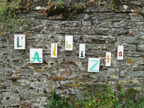 un mur en pierre avec des signes alphabet sur celui-ci dans l'établissement L' ALBIZIA, à Saint-Martin-de-Sallen