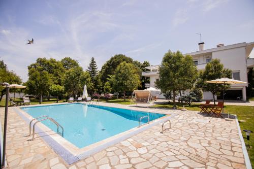 een groot zwembad in een tuin met een gebouw bij Zeusplace PoolVilla Natura in Kateríni