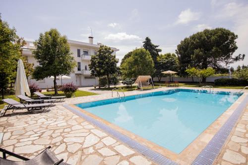 a large swimming pool with chairs and a building at Zeusplace PoolVilla Natura Paralia Katerini in Katerini
