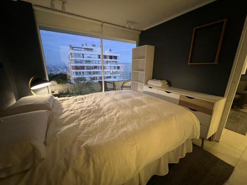 a bedroom with a white bed and a large window at Oceana Suites Capital in Santiago