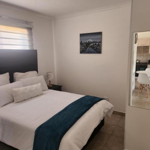 um quarto com uma cama branca e uma fotografia na parede em Two Bedroom townhouse THE PINES ALBERTSDAL em Alberton