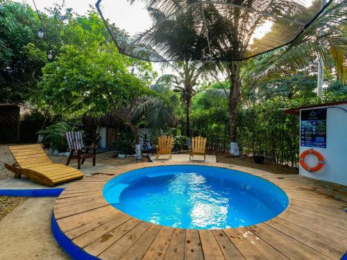 a pool on a wooden deck with chairs and a table at Los Almendros Palomino Hostel in Palomino