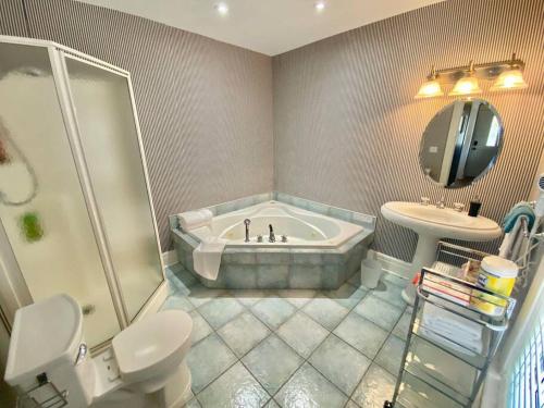 a bathroom with a tub and a toilet and a sink at Adorable 2-bedroom unit with jacuzzi beside falls in Niagara Falls
