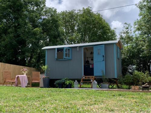 a blue shed in a yard with a table at St. Kew Shepherd Huts in Wadebridge