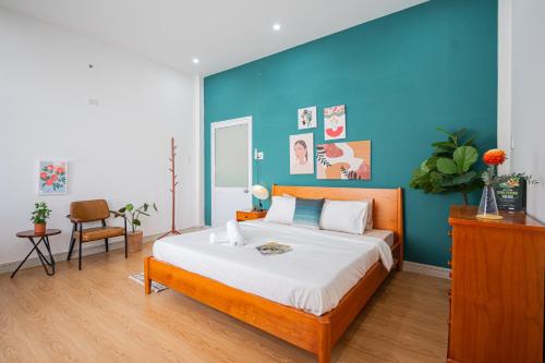 1 dormitorio con 1 cama grande y pared azul en Fika Homestay Nguyên Căn 600m2 - Trung Tâm Quy Nhơn, Cách Biển 50m en Quy Nhon