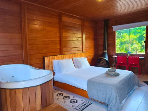 een slaapkamer met een bed en een bad bij Refúgio Allamanda Flats in Visconde De Maua