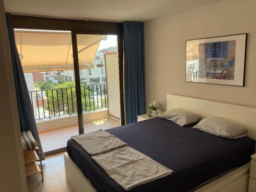 a bedroom with a large bed and a balcony at Sunny apartment with pool in Tossa de Mar