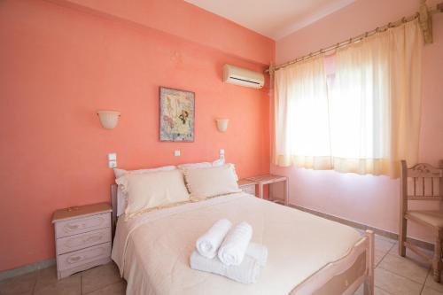 a bedroom with orange walls and a bed with towels on it at Seralis Pelion in Afissos