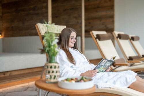 a woman sitting in a chair with a book at Löckerwirt in Sankt Margarethen im Lungau