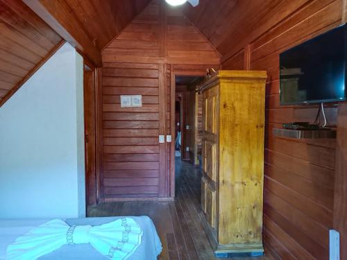 een kamer met een bed en een flatscreen-tv bij Refúgio Allamanda in Visconde De Maua