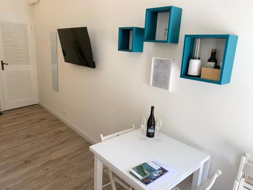 uma mesa branca com uma garrafa de vinho na parede em Casetta Lorica Porto Santo Stefano em Porto Santo Stefano