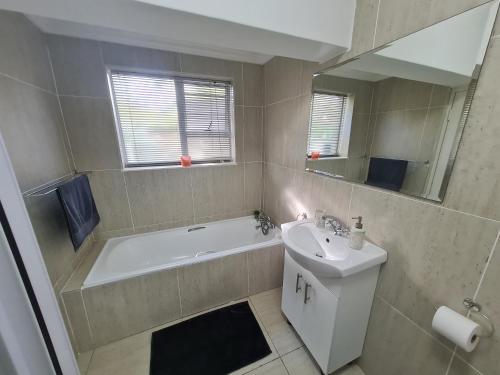 a bathroom with a tub and a sink and a bath tub at Sandpiper Self Catering in East London