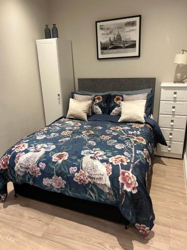 a bedroom with a bed with a floral bedspread at Sweet Swan House in Rickmansworth